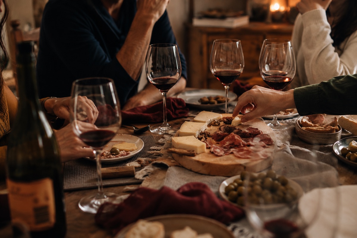 Amigos compartiendo vino y quesos en una sobremesa